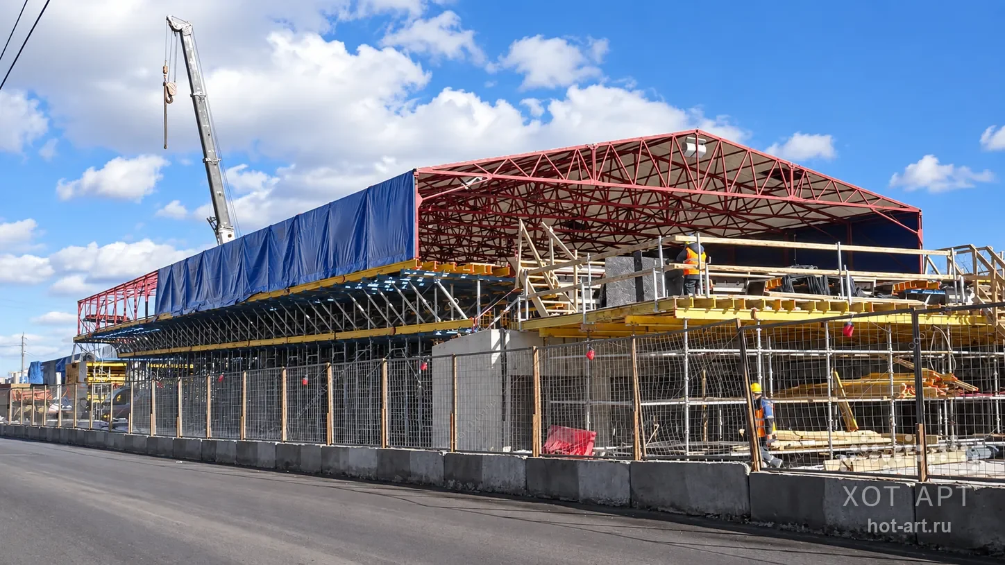 Тентовый тепляк 16,5×130×2,2 м в Москве: красный каркас закрыт синим полотном, автокран подаёт конструкции