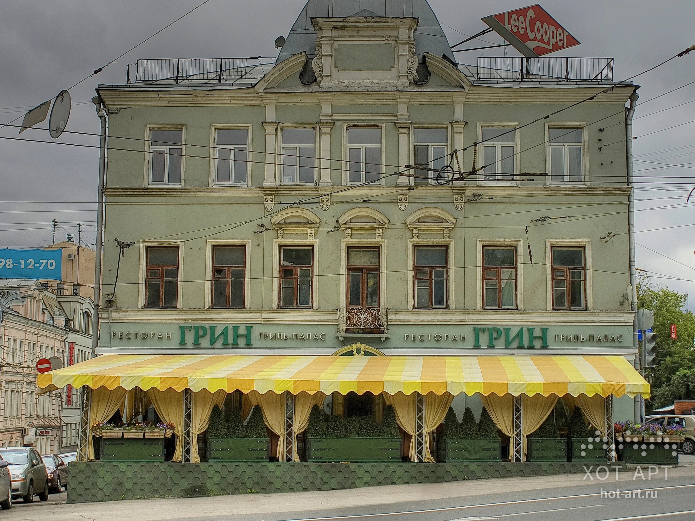 Летняя веранда ресторана «Грин Гриль Пэлас» 6×18×3 м в Москве: жёлто-белый полосатый тент на всю ширину фасада, ажурные фермы и драпировки по периметру